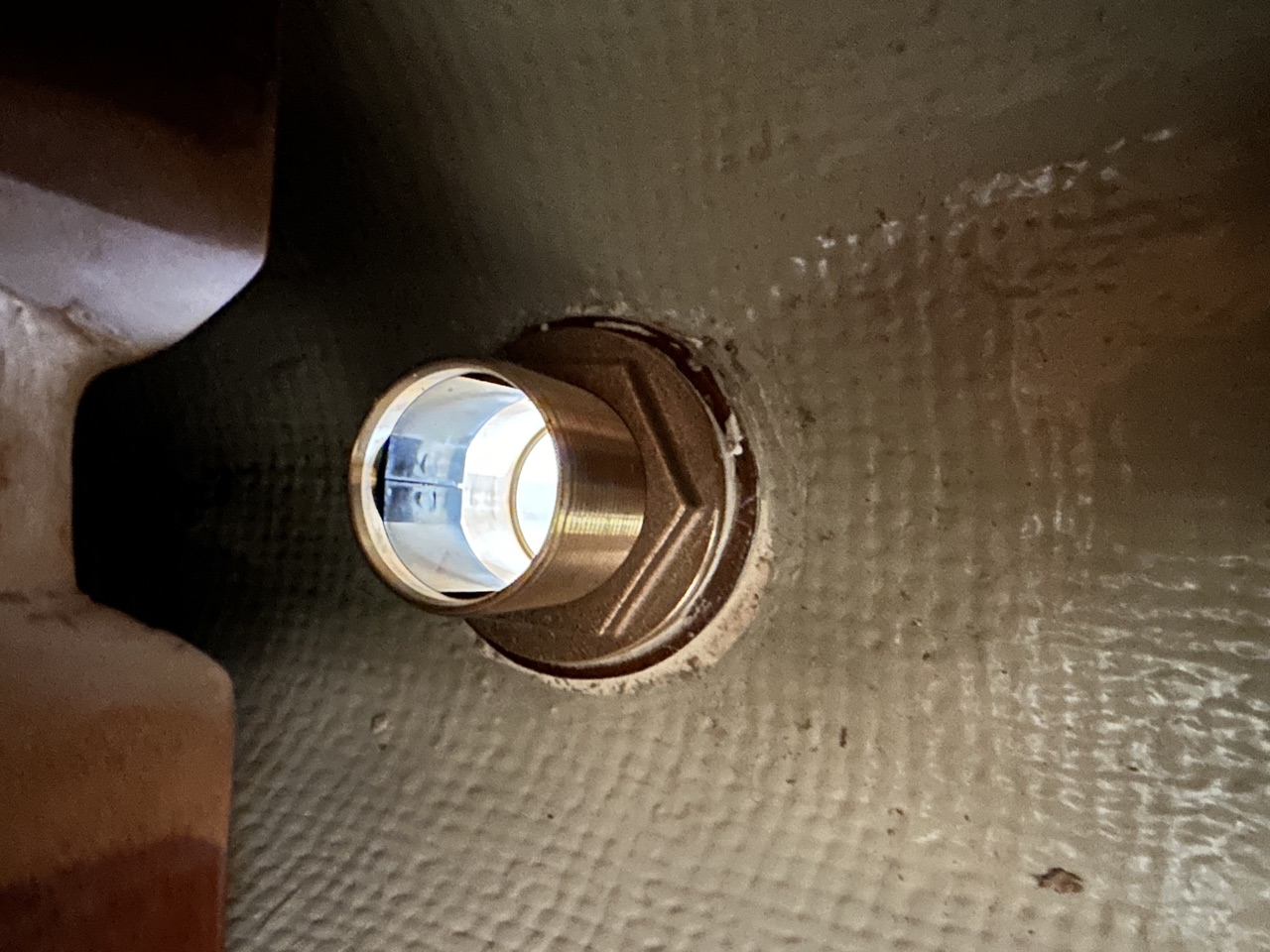 Close-up interior view of the Airmar DST810 bronze thruhull seated in the hull with the transducer element visible
