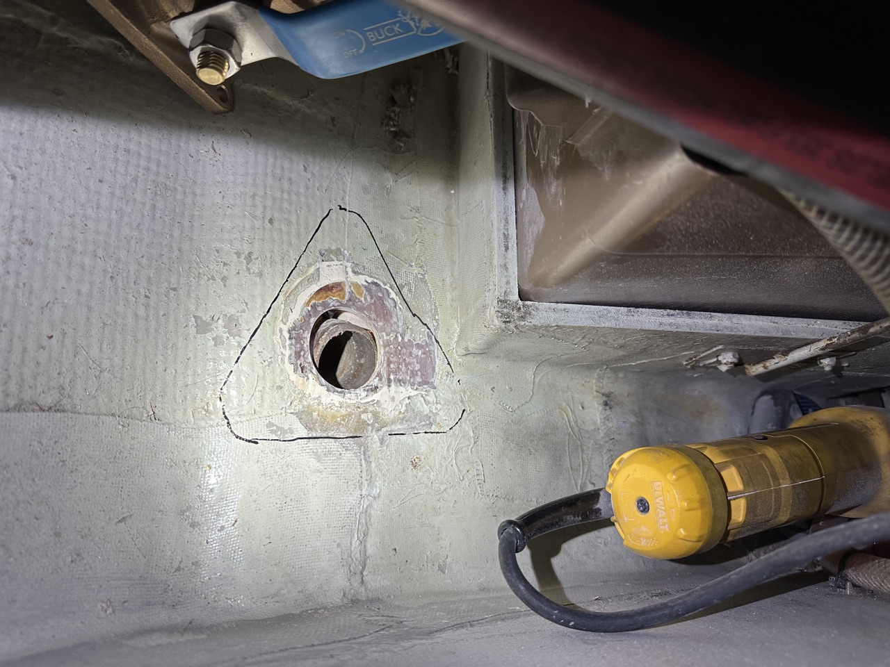 Old thruhull removed from the hull, with the triangular outline traced and the corroded fitting visible