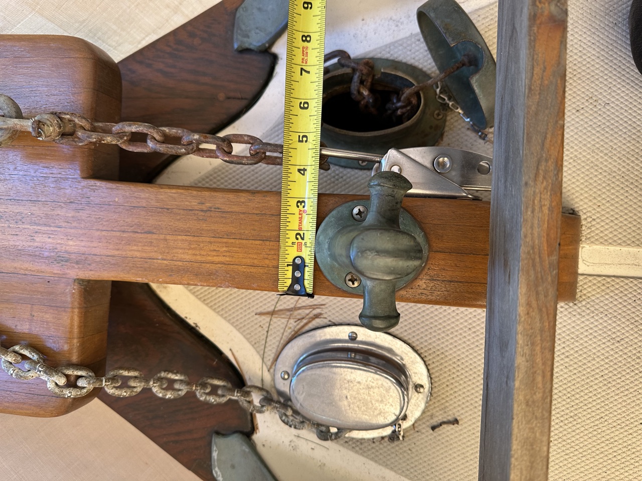 Measuring the existing bowsprit width with a tape measure to compare against windlass footprint