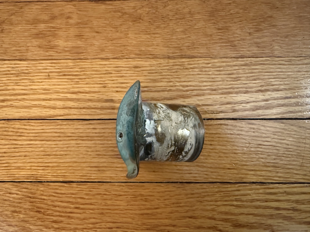 Old brass foredeck scupper fitting removed from the boat, showing corrosion and deteriorated sealant on the base