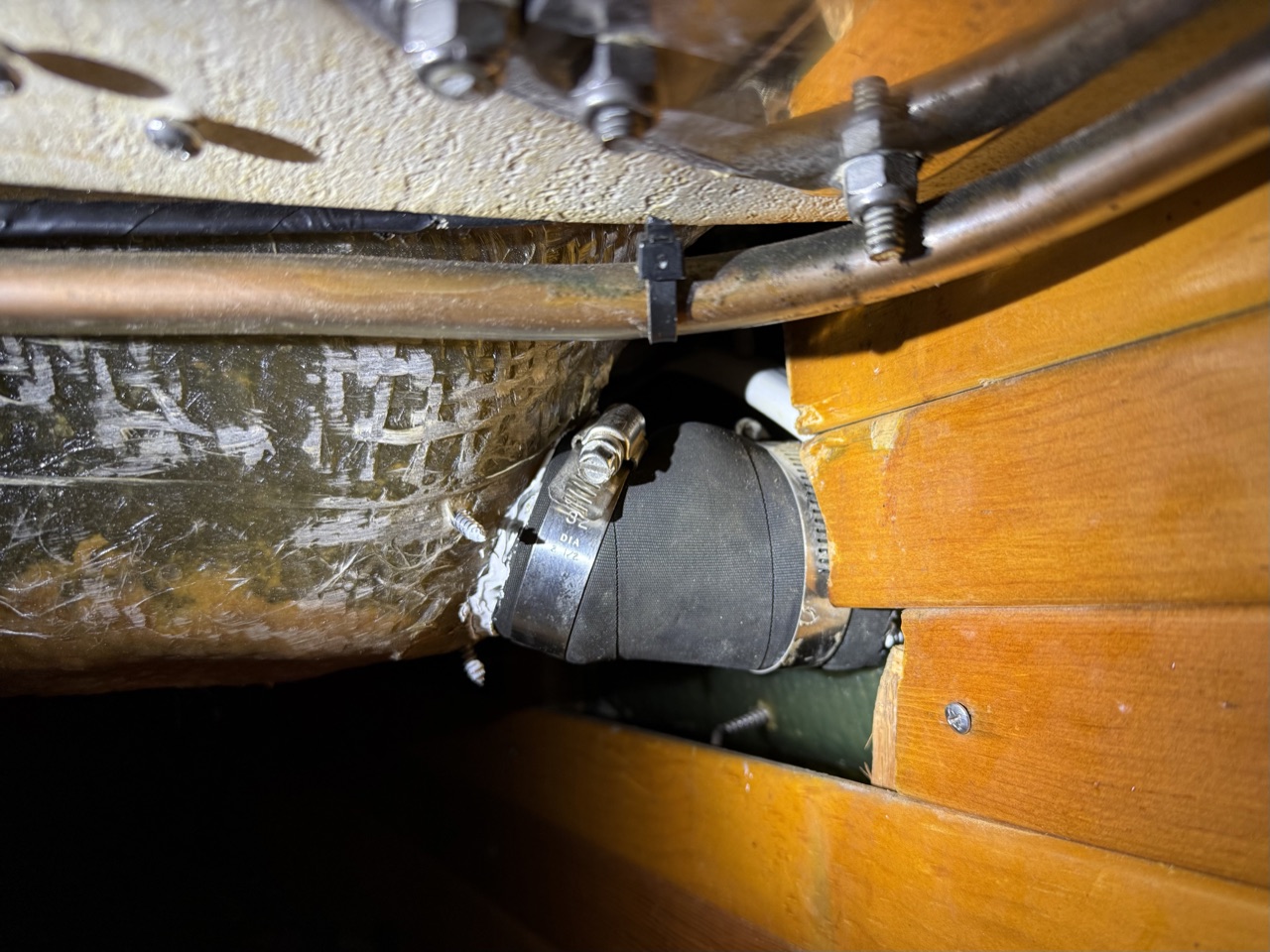 New scupper hose installed inside the boat with stainless hose clamps, running downhill to the hull exit