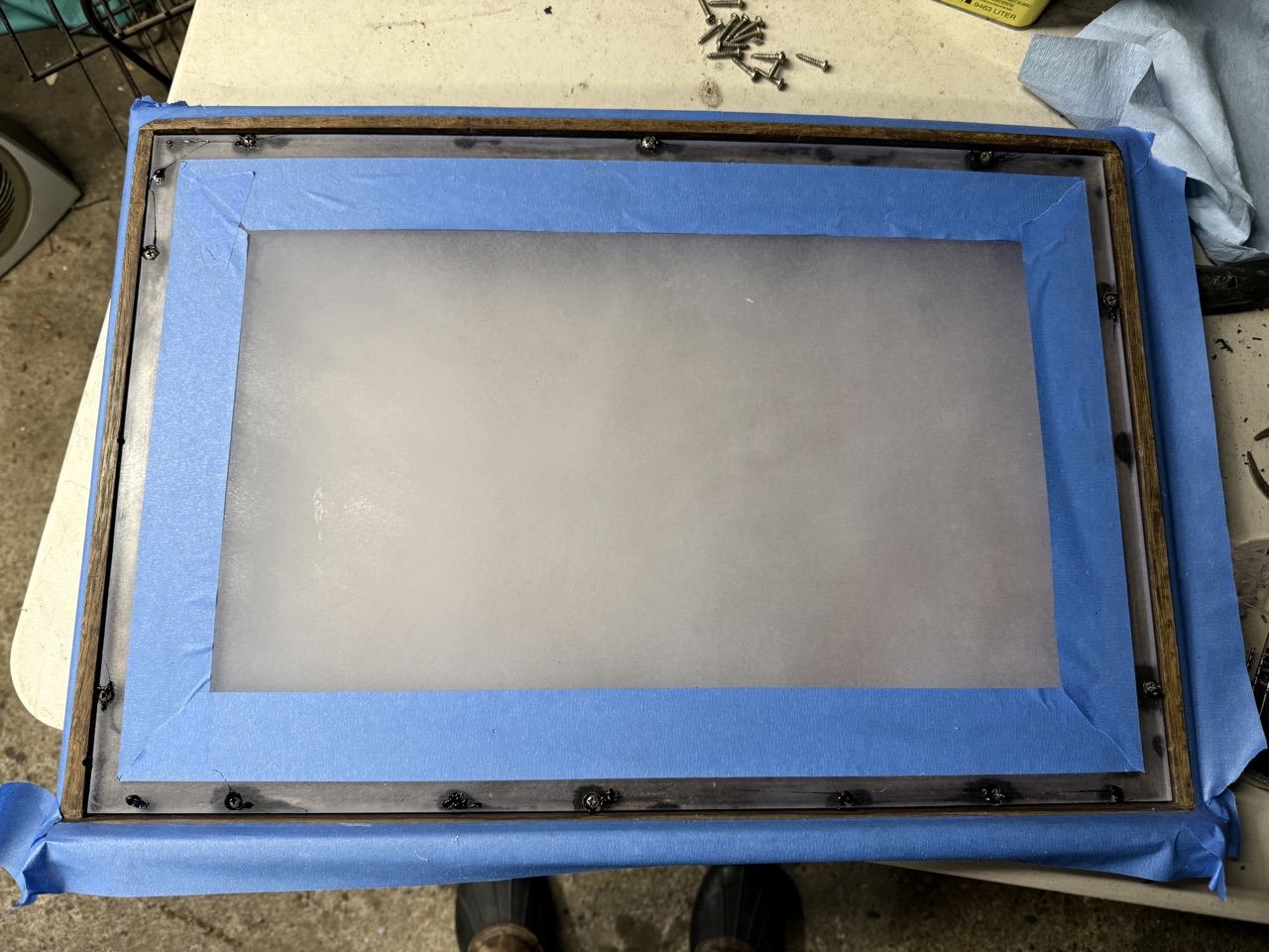 Aft cabin hatch with 4200 applied and screws run through the teak frame, blue tape still in place