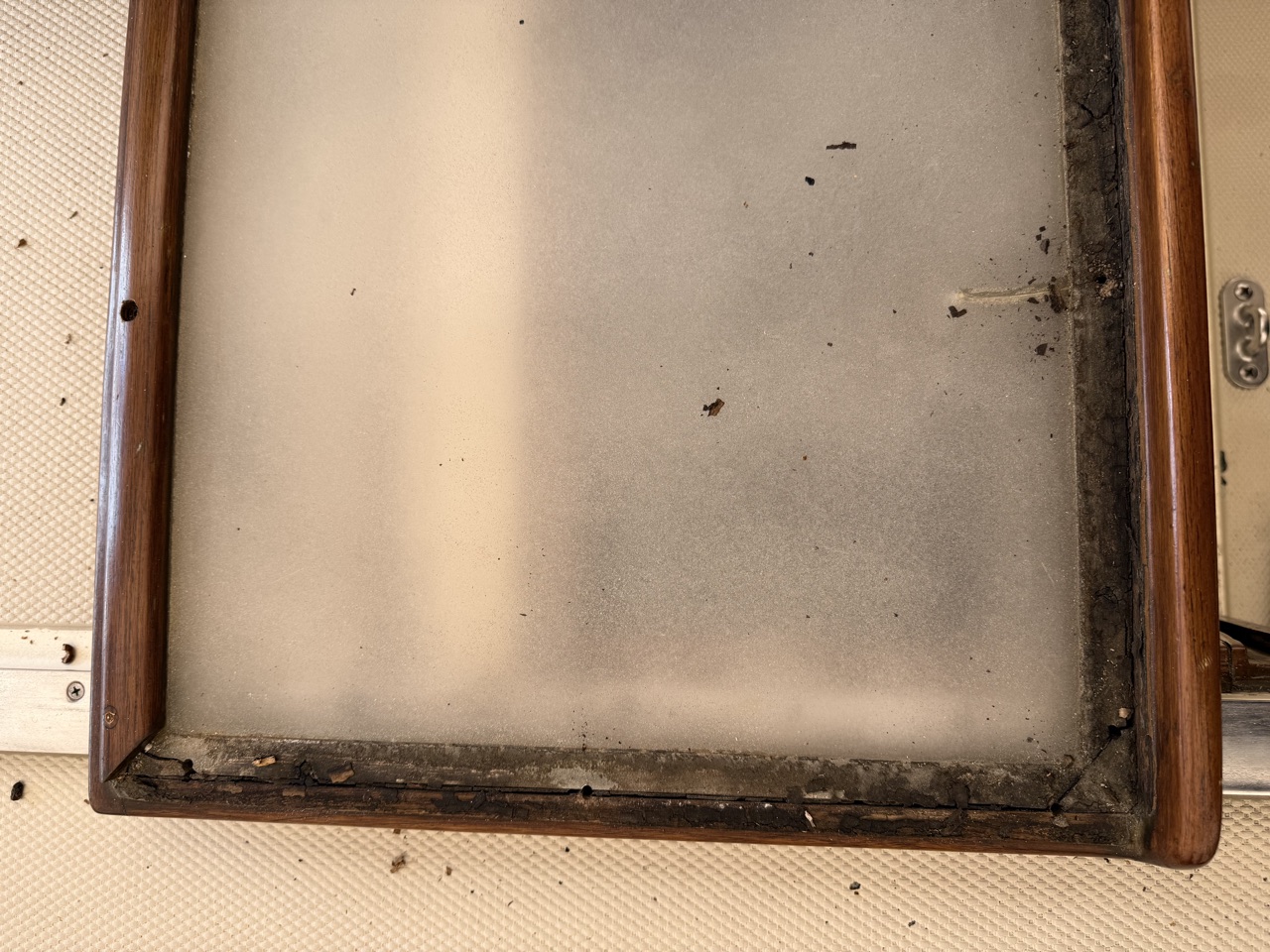 Underside of the original aft cabin hatch panel showing cracked and failed sealant along the teak frame