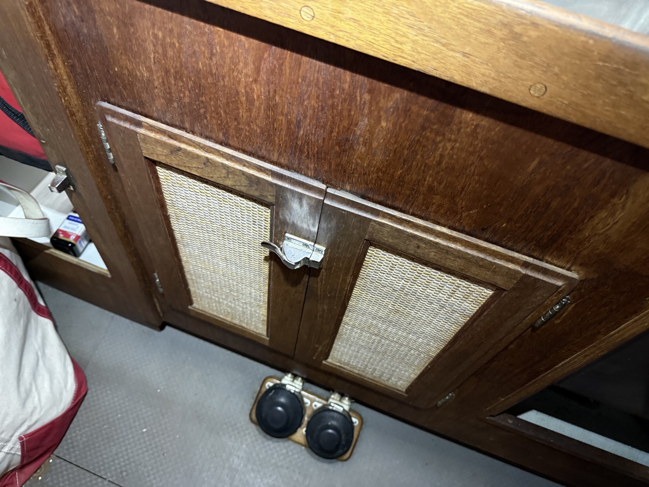 Under-sink galley cabinet doors closed cleanly with no sign of the trash can inside
