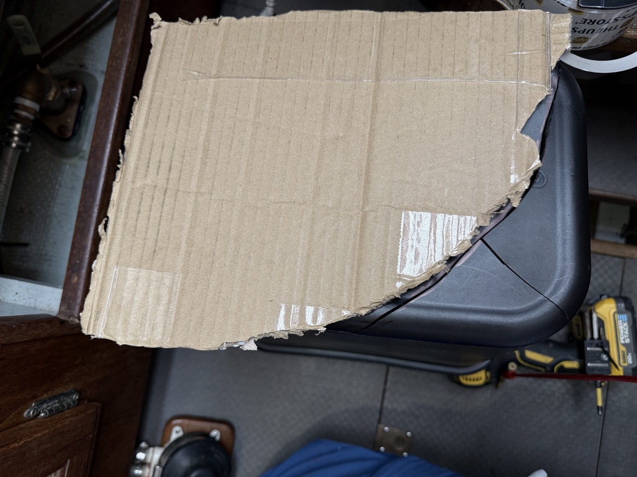 Cardboard template laid on top of the black plastic trash can to mark the cut lines