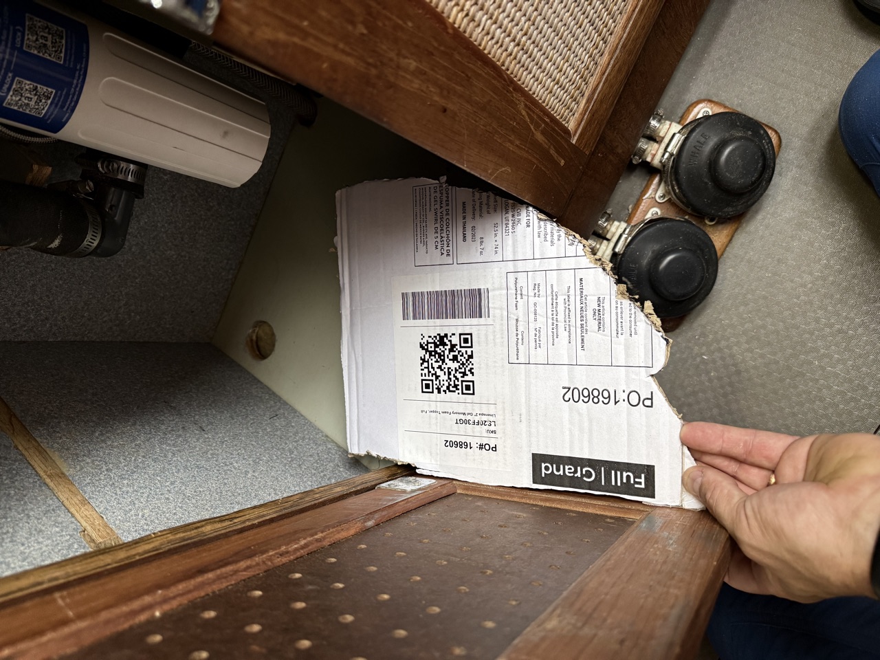 Cardboard template being held inside the open under-sink cabinet door to check fit and clearance