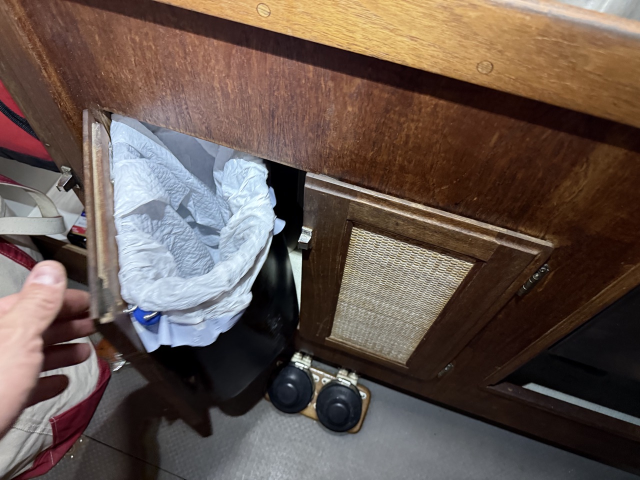 Under-sink cabinet door being pulled shut showing the trash can fitting cleanly inside