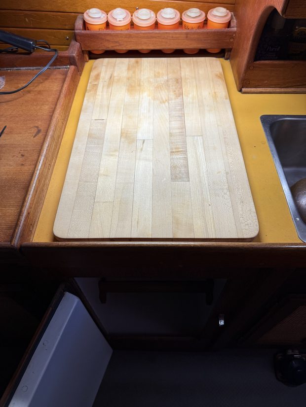 Butcher block cutting board sitting over the closed icebox